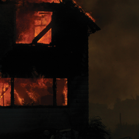 A photograph of a two-story house engulfed in flames