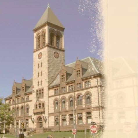 An image of Cambridge City Hall as seen from a slight front angle. The building is a multi-story stone structure with large obelisk shaped central tower above the front door. The photograph has been intentionally aged and is yellowed on one side.