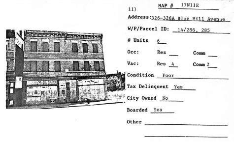A scan of a property at 326-326A Blue Hill Avenue in North Dorchester shows a property with four residential and two commercial units reported. The three-story building has been boarded up. Information to the side of the photograph reveals the auditor found the building to be in poor condition, tax-delinquent and not city-owned.